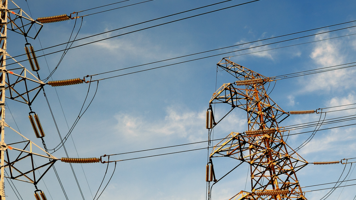 High-voltage transmission towers and power lines against a blue sky