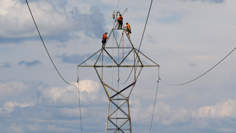 Technicians working on high-voltage transmission tower