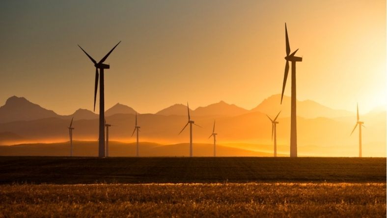 Wind turbines generating power at sunset over open landscape